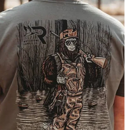 The Roost Sasquatch Duck Hunter Short Sleeve Pocket Tee combines distinctive outdoor-inspired artwork with comfortable wear. Crafted from 100% cotton, this tee features a detailed graphic of a Sasquatch dressed as a duck hunter in a marsh, complete with shotgun and harvested ducks. The front pocket displays the Roost waterfowl logo, adding an authentic touch. Ideal for waterfowl enthusiasts seeking casual, breathable apparel that reflects their passion.