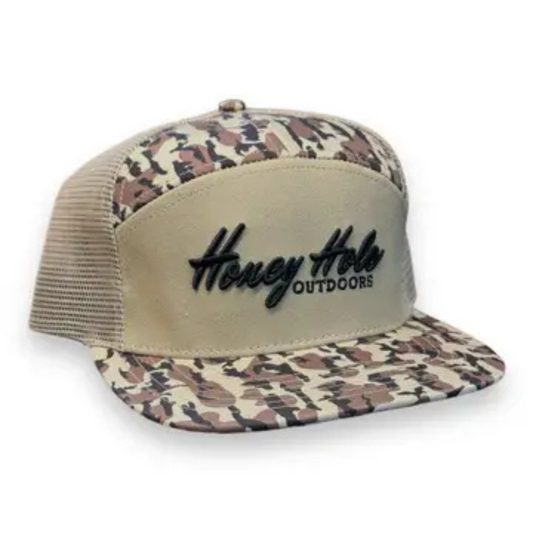 The Honey Hole Outdoors Heritage Duck Boat Camo Snapback 7 Panel&nbsp;Hat combines durability and comfort with a camo bill and top panel, complemented by tan mesh and front panels for breathability. Featuring the Honey Hole Outdoors script on the front, this snapback hat offers an adjustable fit, making it ideal for outdoor enthusiasts seeking style and function during their adventures.