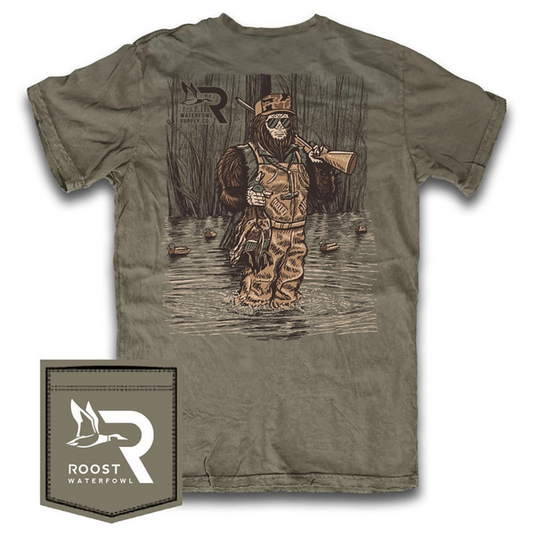 The Roost Sasquatch Duck Hunter Short Sleeve Pocket Tee combines distinctive outdoor-inspired artwork with comfortable wear. Crafted from 100% cotton, this tee features a detailed graphic of a Sasquatch dressed as a duck hunter in a marsh, complete with shotgun and harvested ducks. The front pocket displays the Roost waterfowl logo, adding an authentic touch. Ideal for waterfowl enthusiasts seeking casual, breathable apparel that reflects their passion.