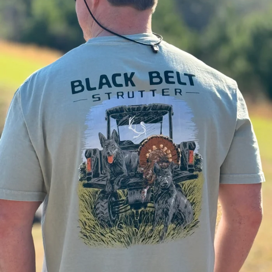 This Short Sleeve T-Shirt by Black Belt Strutter Brand blends organic cotton comfort with a design inspired by southern hunting traditions. Featuring a bold graphic of loyal hunting dogs, a ranger, a strutting turkey, and a rugged off-road vehicle, it captures the thrill of the hunt. The shirt’s soft, breathable fabric in light grey and stone wash green offers unmatched wearability for outdoor enthusiasts. Perfect for those who appreciate authentic style rooted in outdoor heritage.