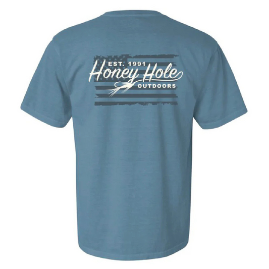 The Honey Hole Outdoors Fly Flag Short Sleeve Tee combines patriotic style with a passion for fishing. Crafted from 100% cotton, it ensures comfort and breathability during outdoor activities. The design features the American flag alongside the Honey Hole Outdoors logo, highlighted by a fishing fly integrated into the script, reflecting your love for angling. Durable and stylish, this tee is ideal for those who value both heritage and their outdoor pursuits.